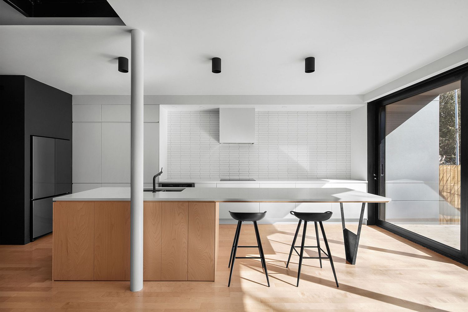 Minimal kitchen of the Montreal home in wood and white with black that anchors it