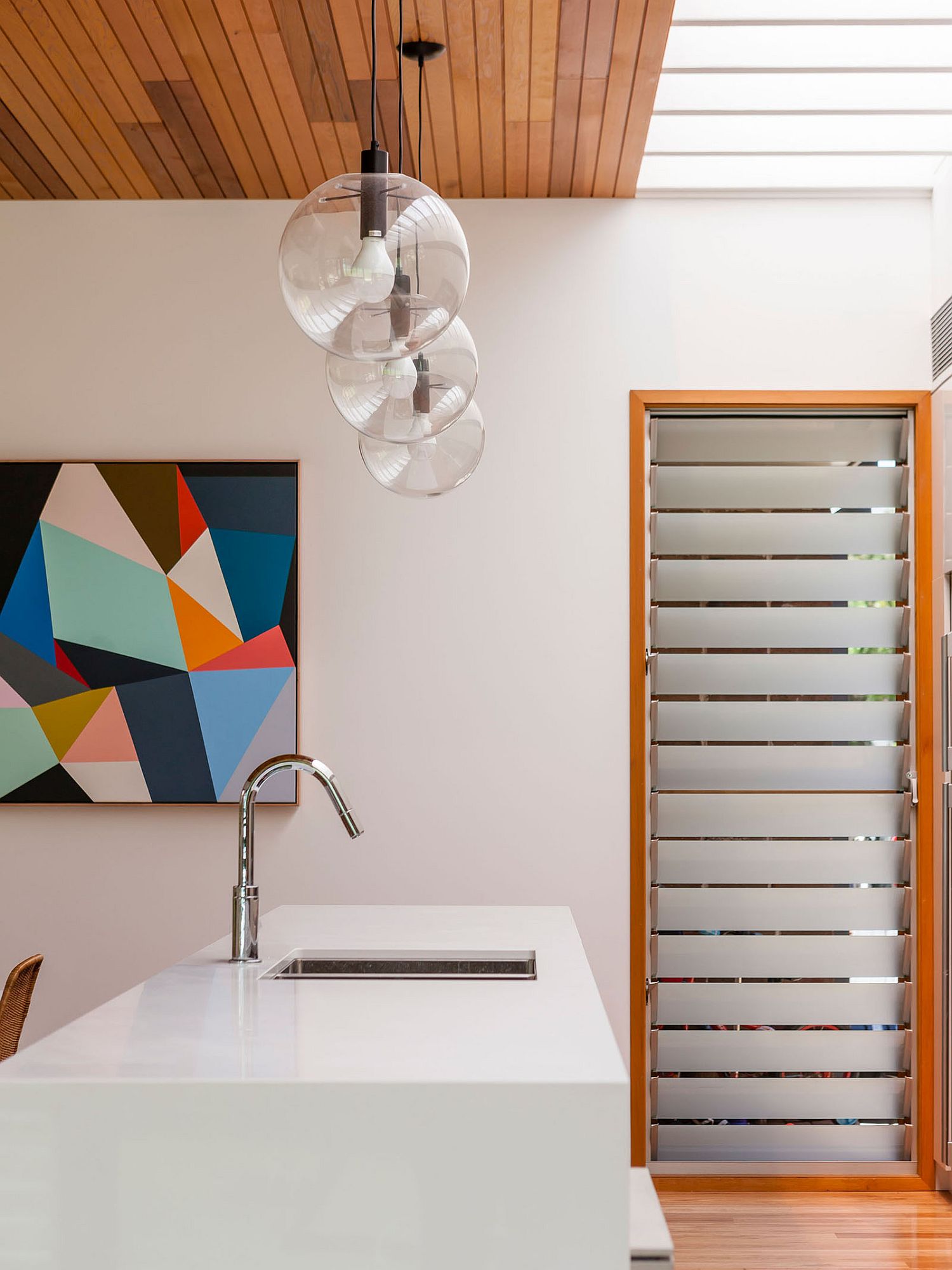 Contemporary kitchen in white utilizes wood and glass beautifully