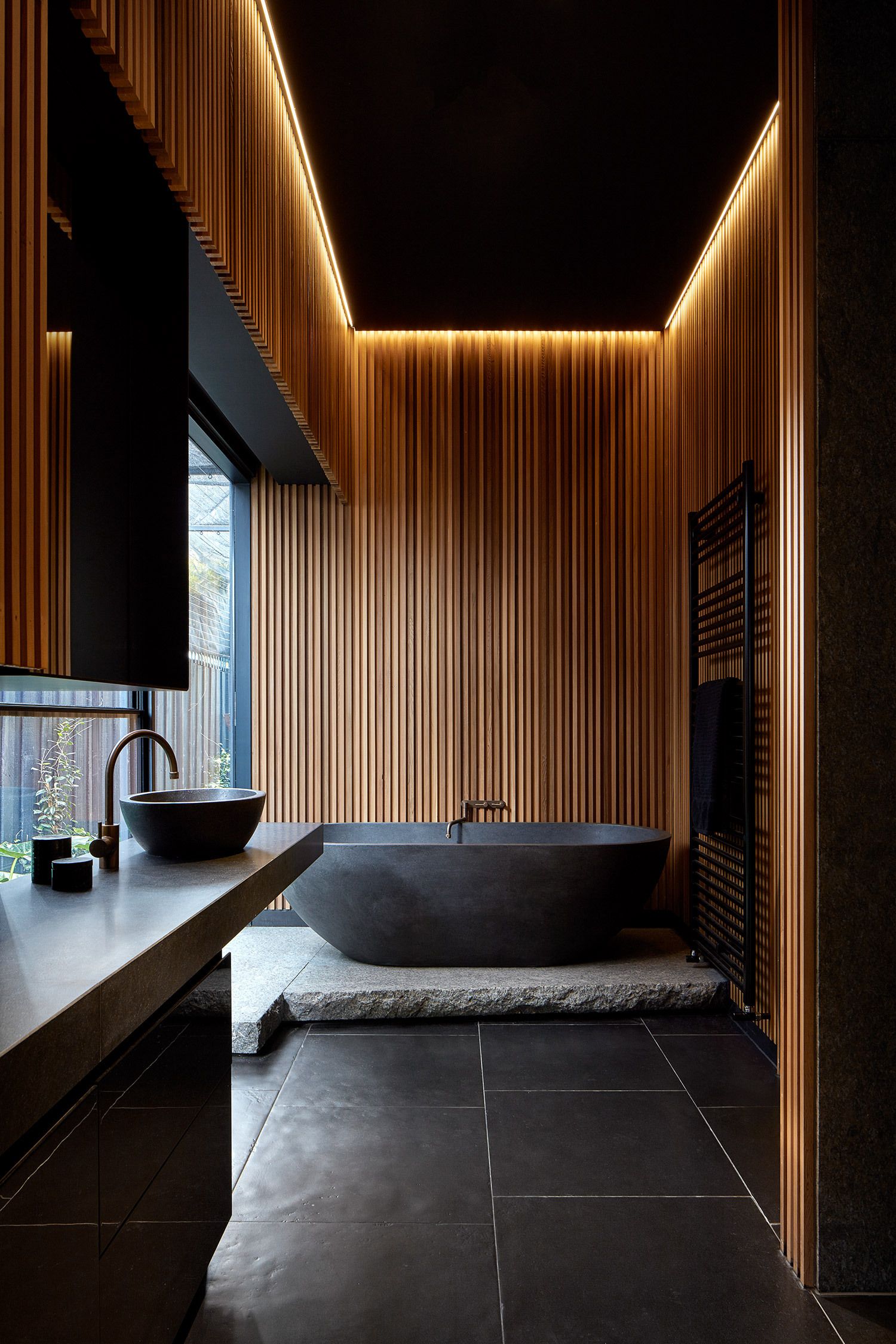 Dark wood and natural stone elements give the bathroom a stunning visual appeal