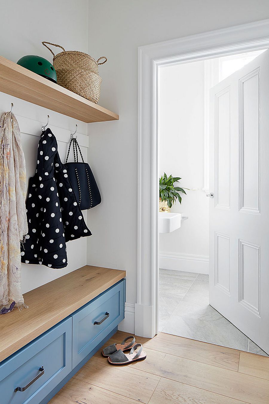 Entry-room-with-a-bench-in-wood-floating-shelves-and-cabinets-in-blue-for-storage