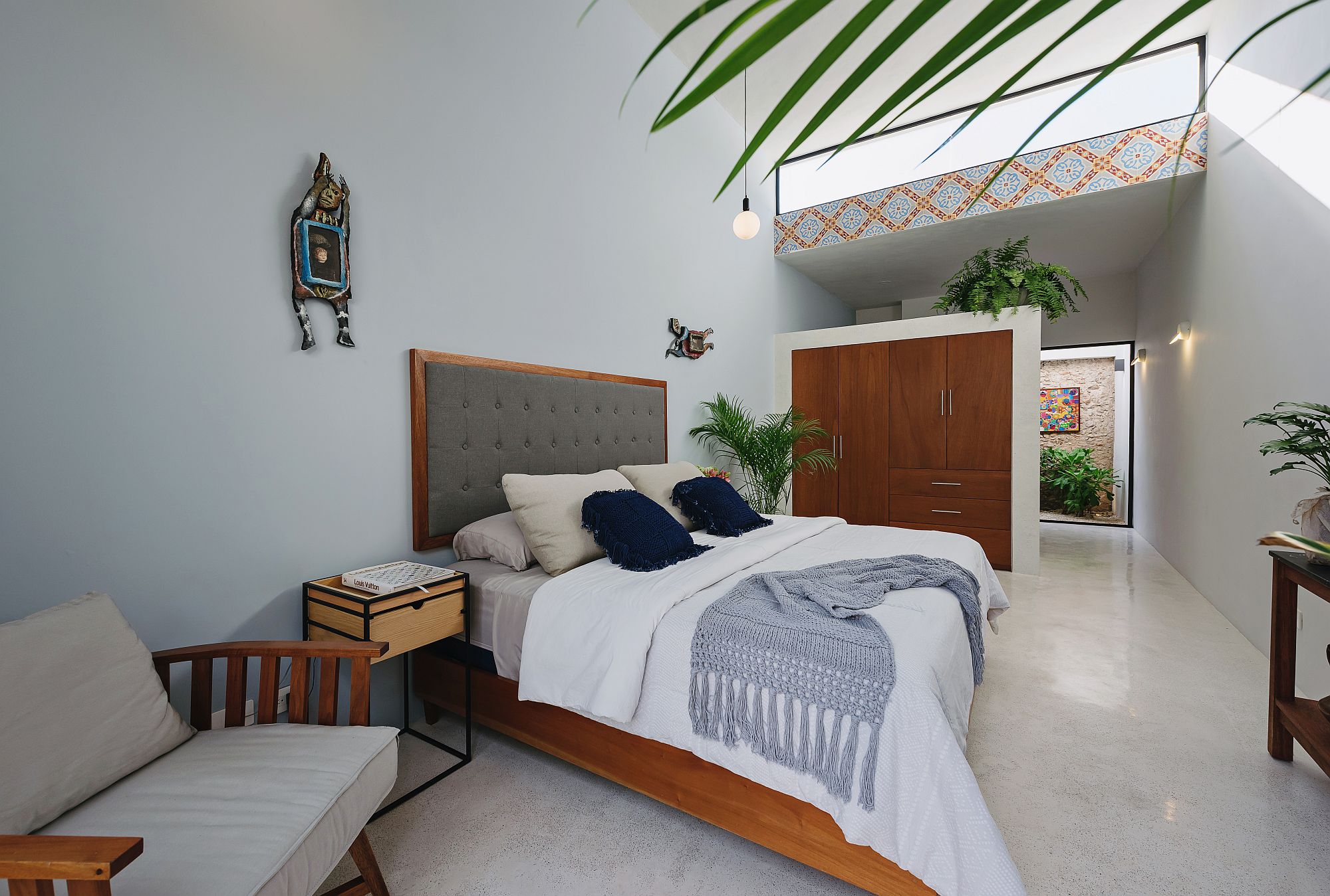 Modern relaxing bedroom in white with warm wooden elements and a dash of color