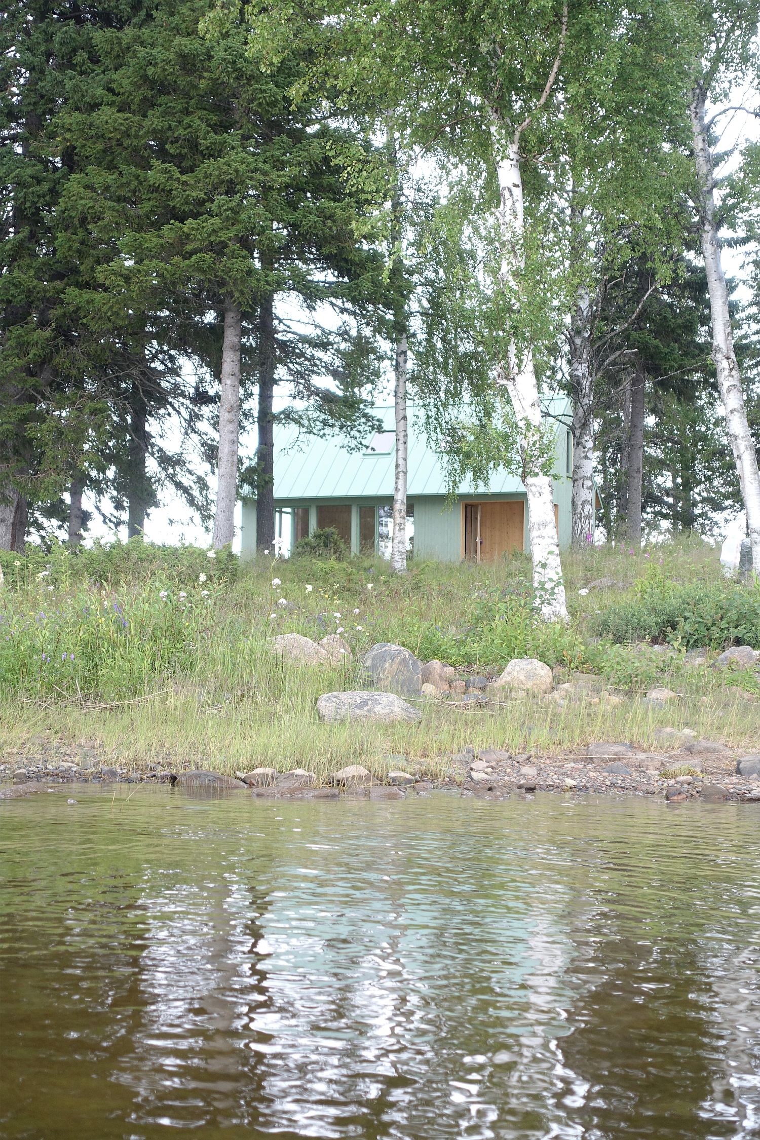 Cabin in light green on a forested Swedish island