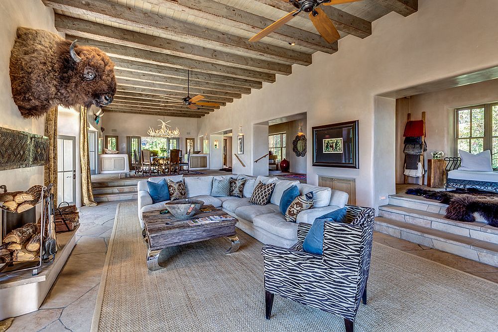 Large living room with Southwestern style, featuring many ceiling beams and two fans.