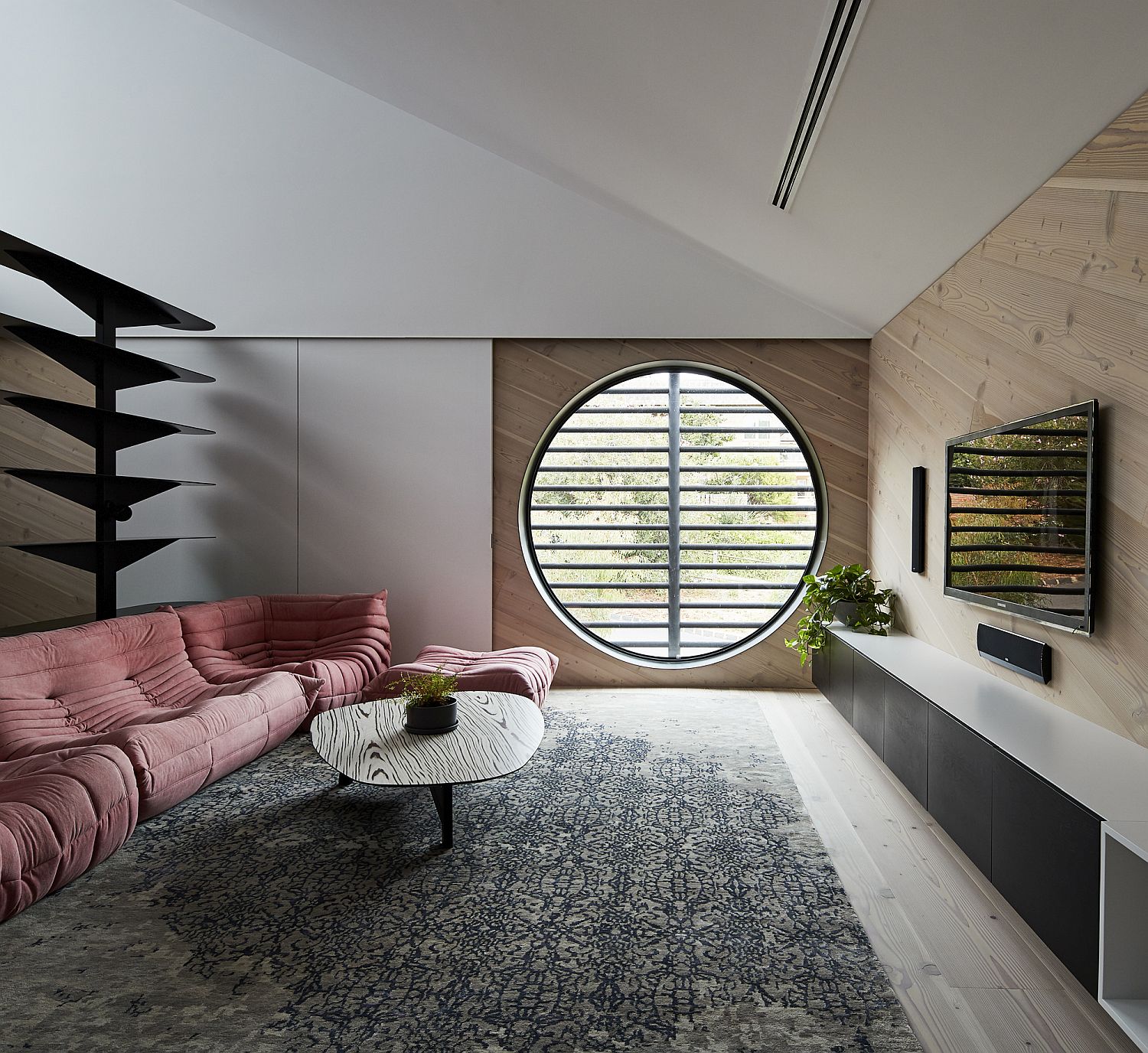 Round window and plush pink sofa add a different dynamic to the room