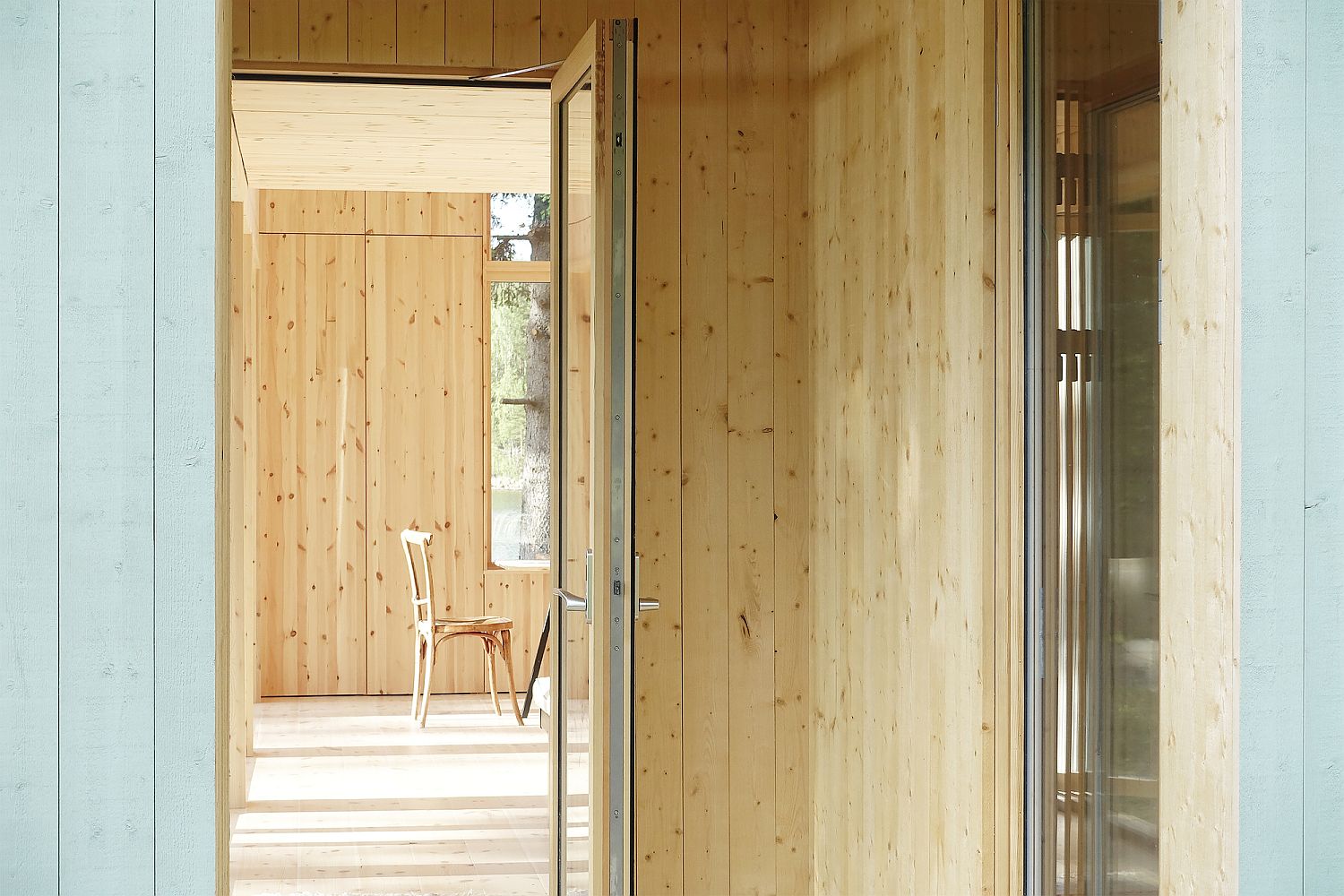 Unassuming minimal cabin design in wood with windows all around