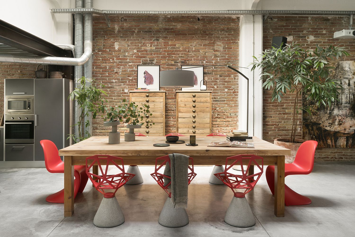 Chairs in red add color to an otherwise neutral dining space with brick wall