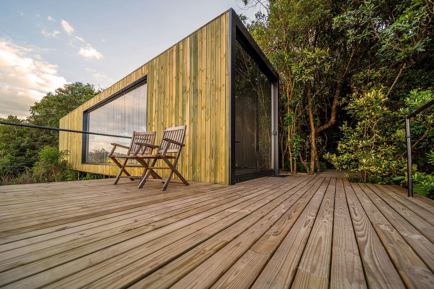 Deck and outdoors of the cain draped in wood and surrounded by greenery