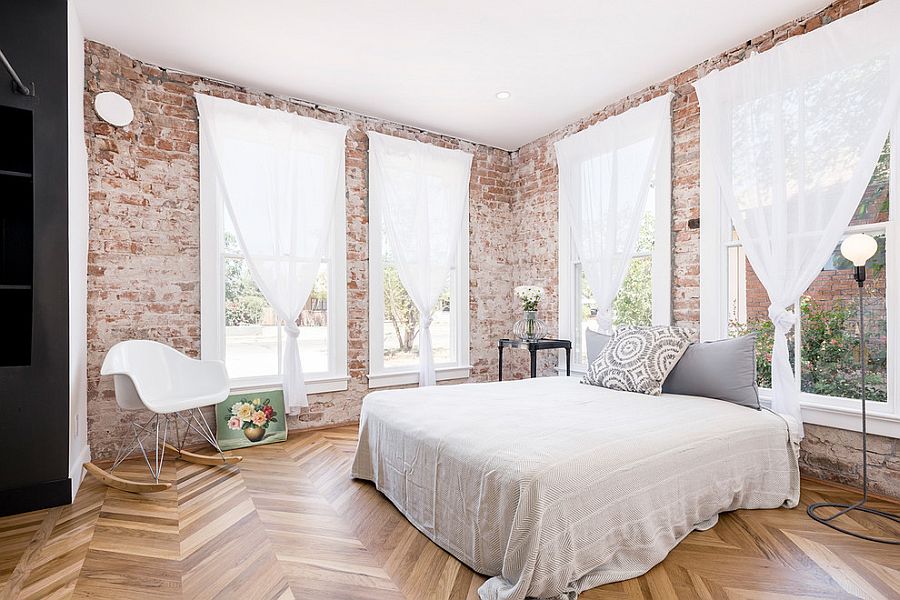 Gorgeous bedroom with wooden floor, brick walls and white sheer curtains