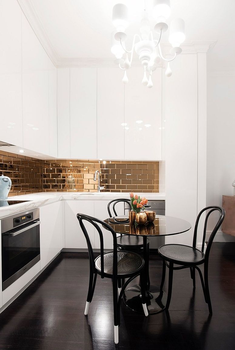 Gold mirrored backsplash coupled with chandelier in the tiny white modern kitchen