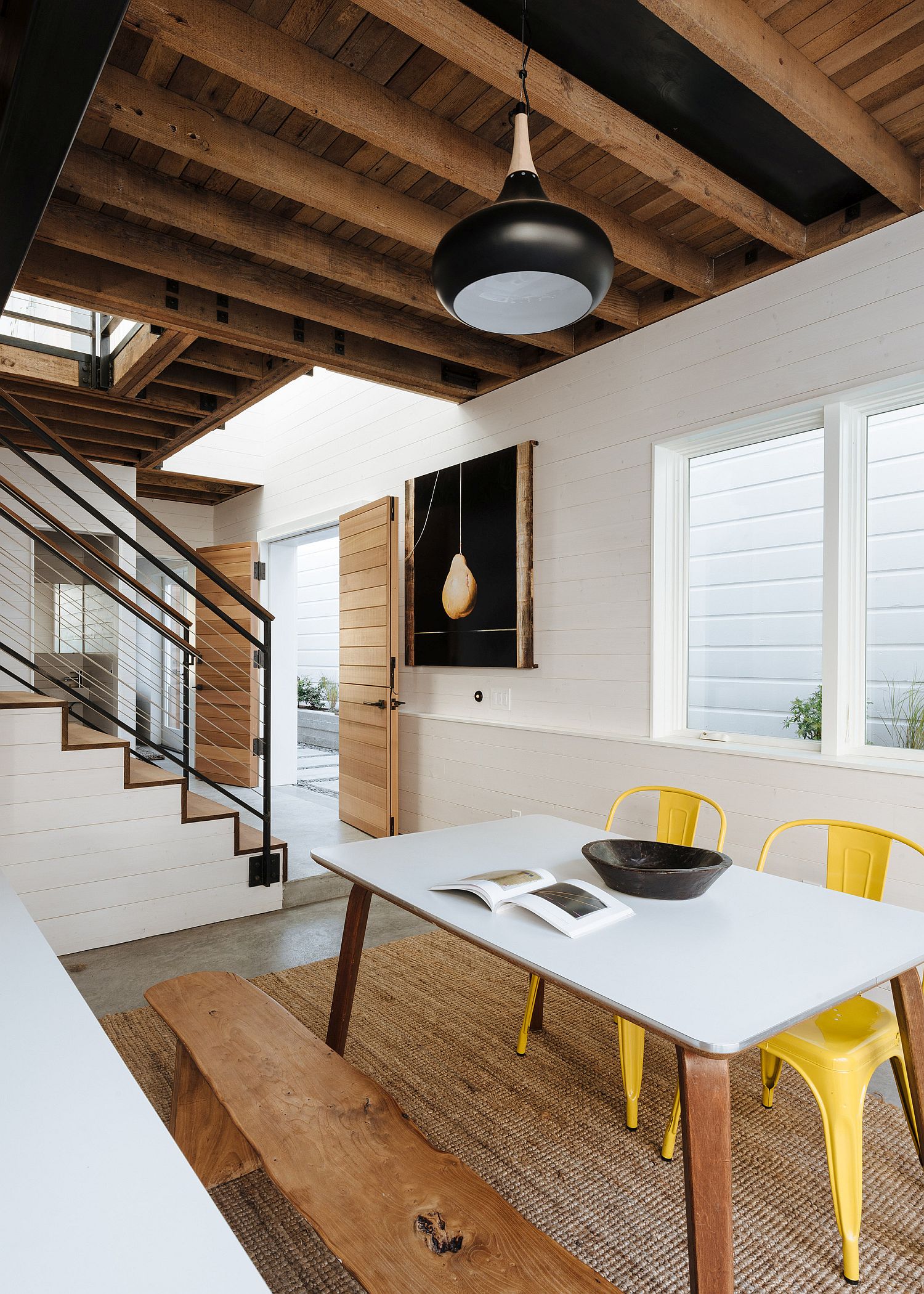 Stylish chairs in yellow add pops of color to the dining space in white and wood