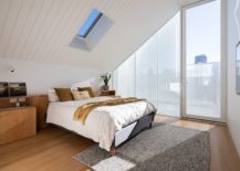 Bedroom-with-slanting-ceiling-skylight-and-glass-walls-feels-spacious-and-modern-217x155