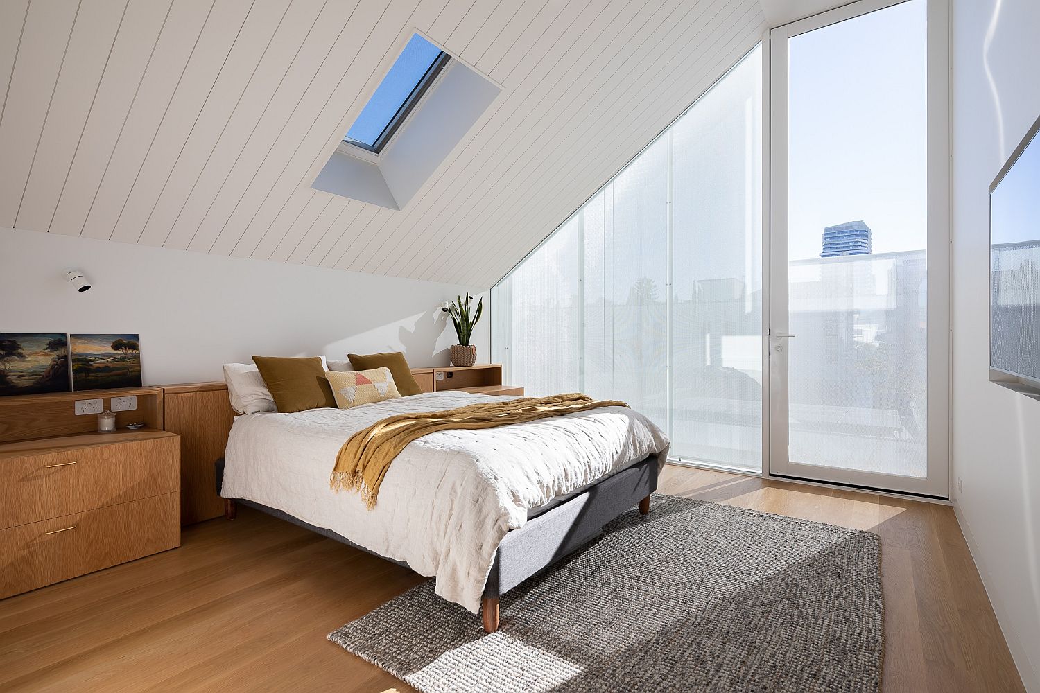 Bedroom-with-slanting-ceiling-skylight-and-glass-walls-feels-spacious-and-modern