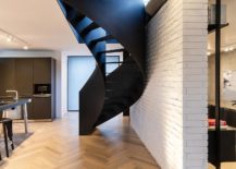 Brick-wall-divides-the-lower-level-of-the-house-and-offers-white-backdrop-for-the-spiral-staircase-in-black-217x155
