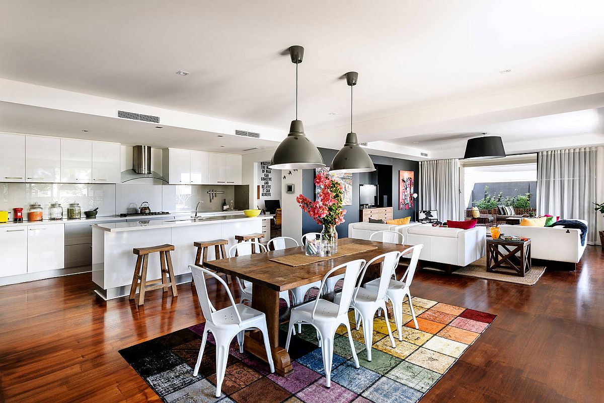 Bright multi-colored rug and oversized pendant lights for the modern dining room next to the kitchen