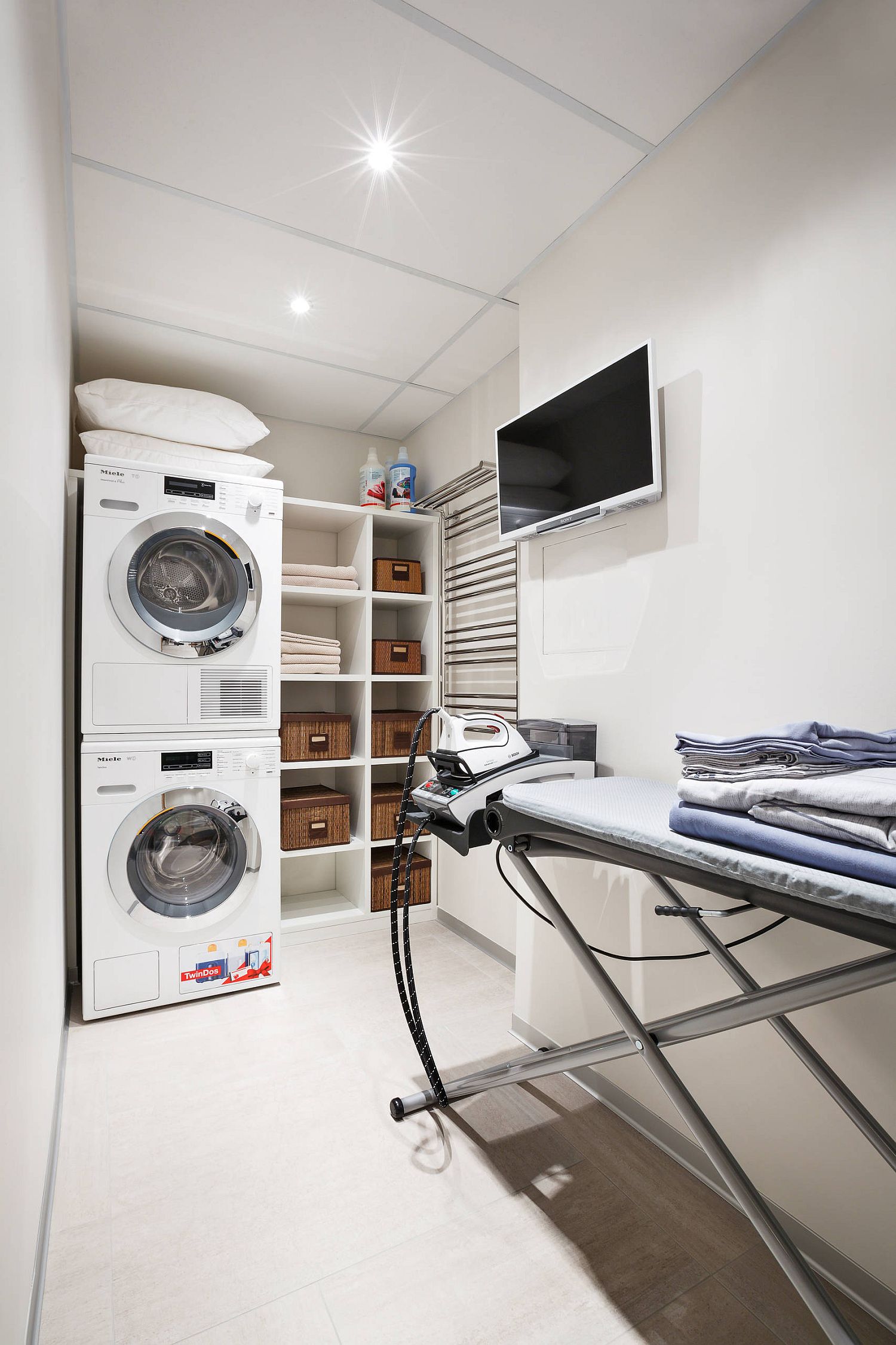 laundry room featuring television above ironing area