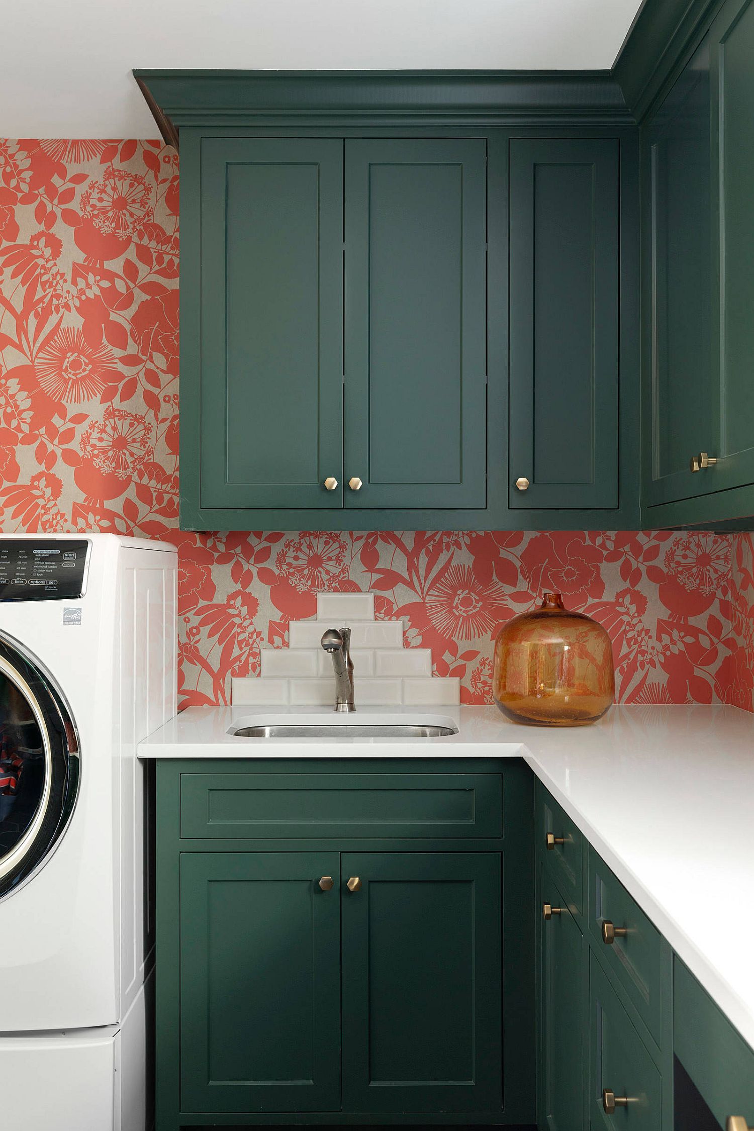 dark green cabinets with coral floral wallpaper in laundry area