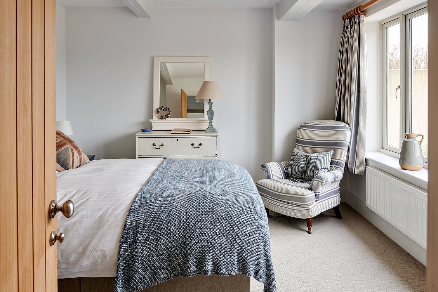 Comfy chair in the corner adds additional sitting space in the small bedroom