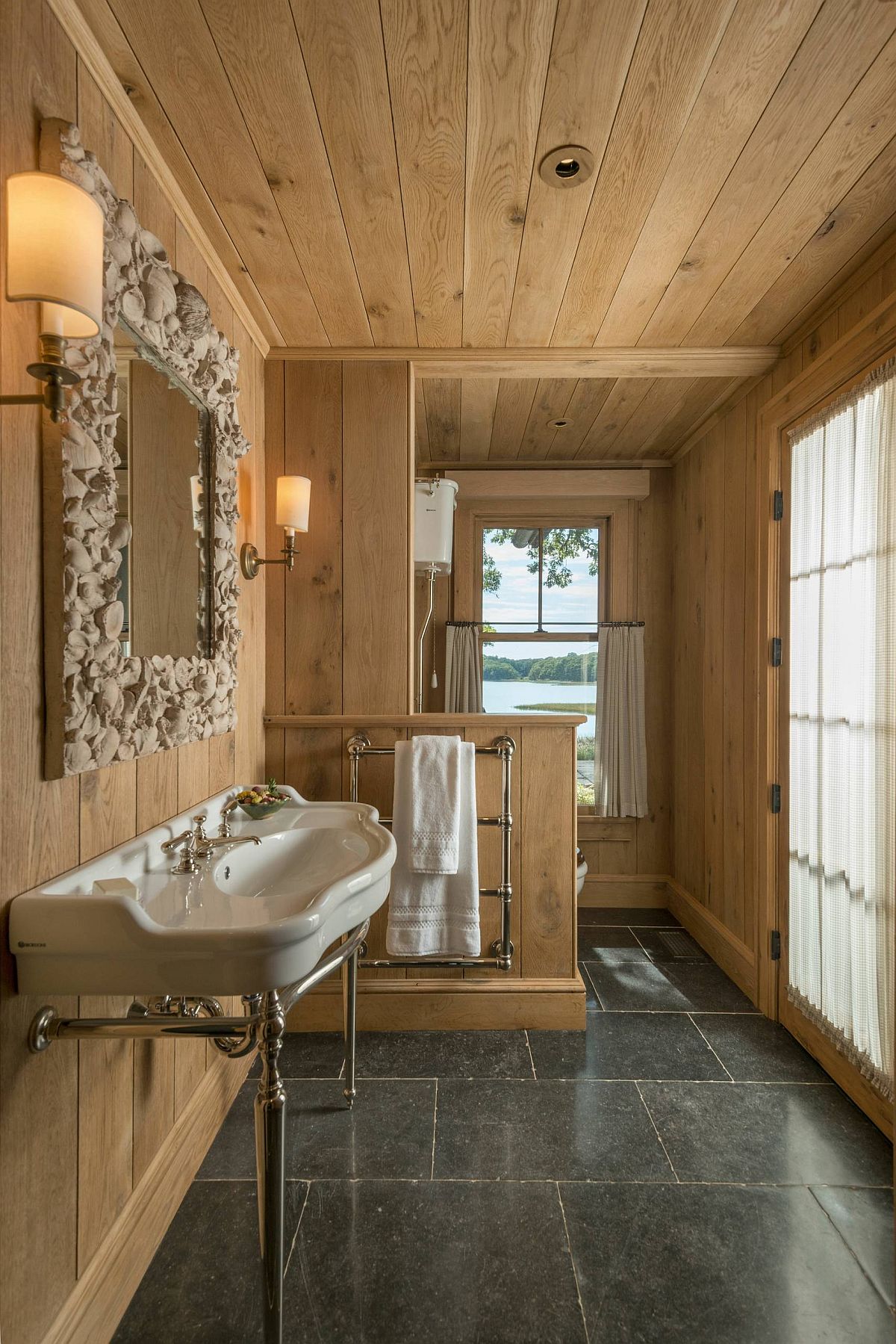 Custom mirror frame for the small rustic bathroom fetauring wood walls and stone flooring