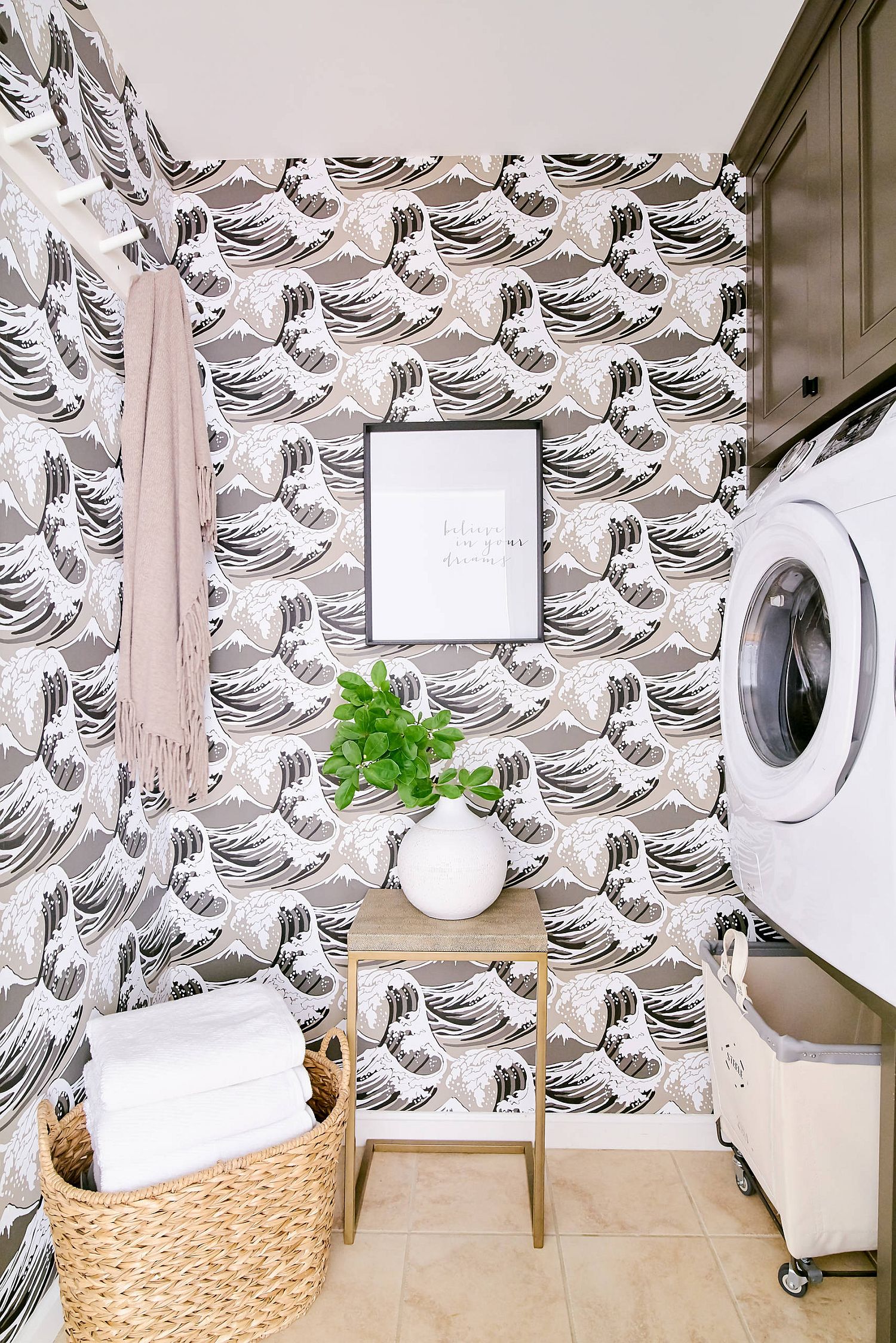 small laundry nook with wallpaper featuring brown, white, and pink ocean waves