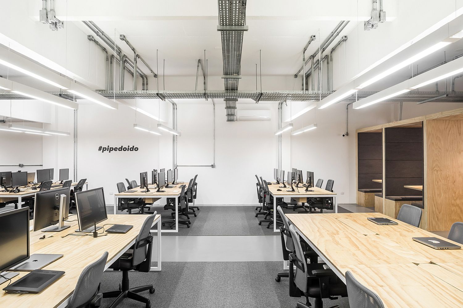 Exposed duct pipes and the flooring bring industrial charm to the modern workspace