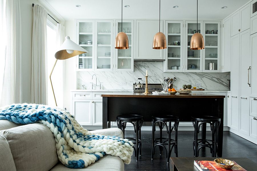 Glittering metal pendants stand in contrast to the light white backdrop and marble backsplash