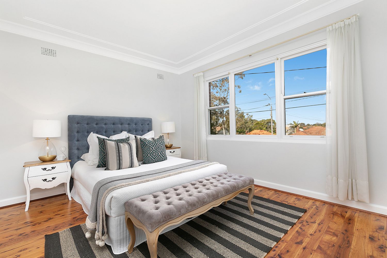 Gray bench at the foot of the bed is a fetaure that brings additional comfort and style to the small bedroom