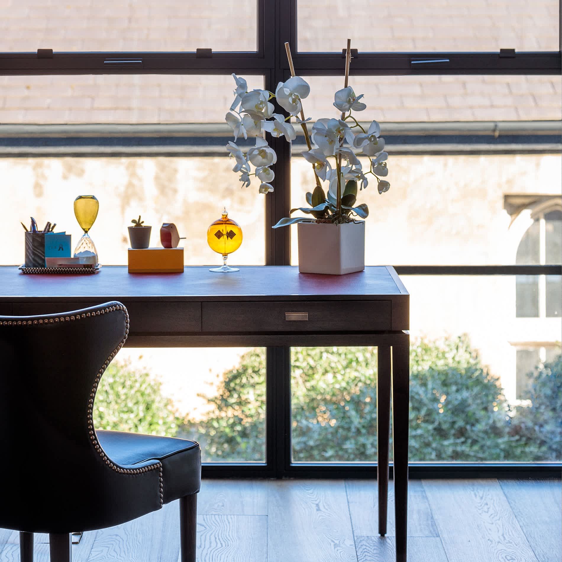 Home workstation next to the glass wall is organized in an uncluttered fashion