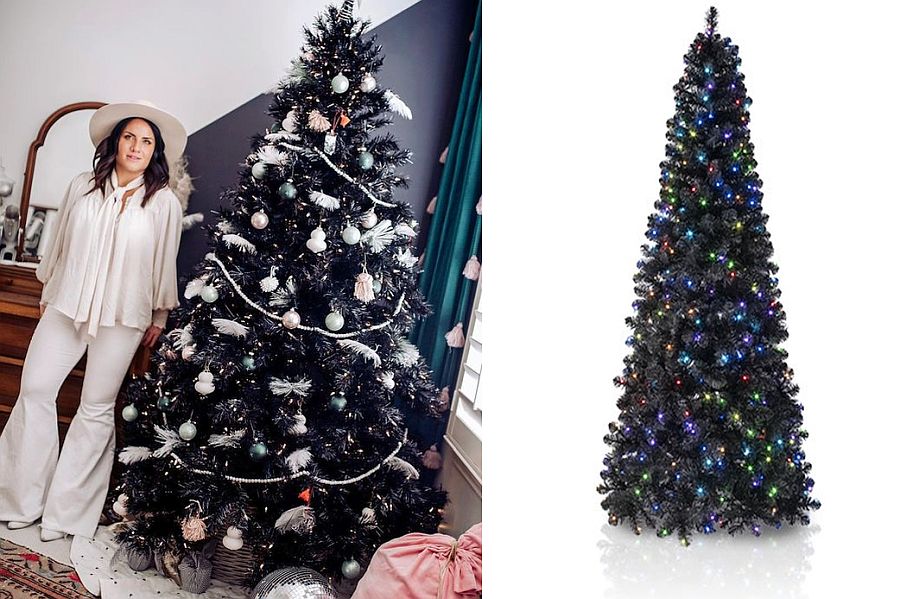 Woman in white clothes standing beside a decorated black Christmas tree.