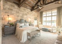 Rustic-farmhouse-style-bedroom-has-a-wooden-ceiling-and-weathered-stone-walls-217x155