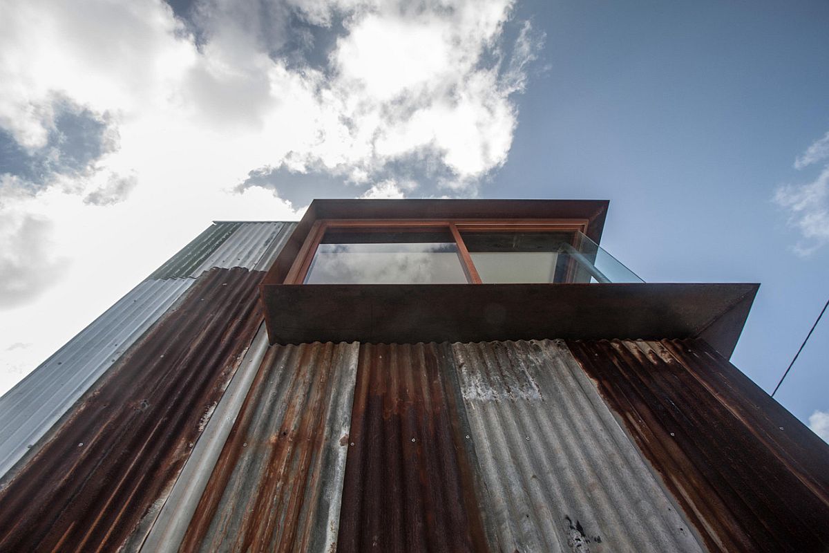 Salvaged and rusted metal covers the facade of the house