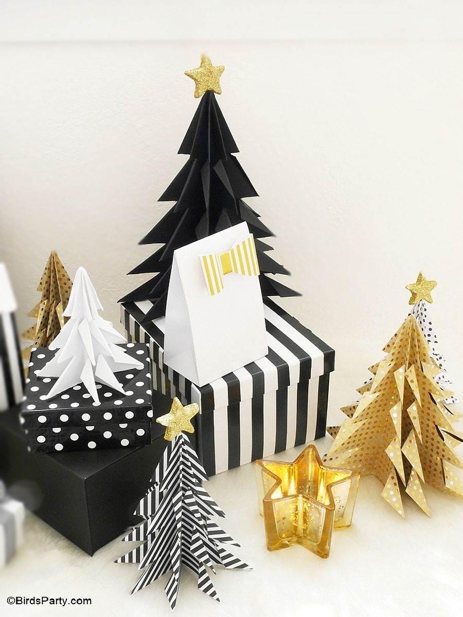 Small black Christmas tree with gold star topper beside a gold Christmas tree and others.