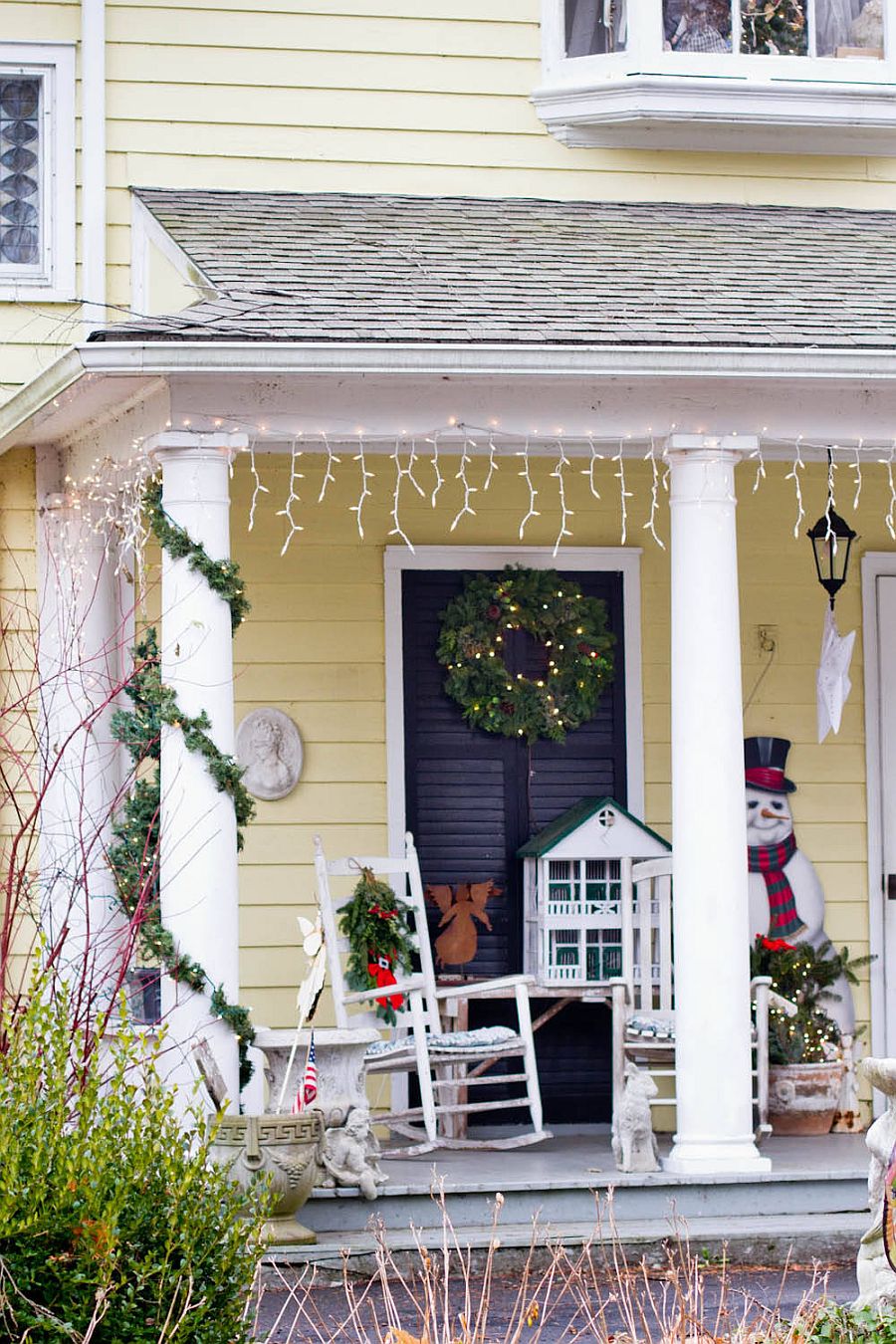 Snowman, string lighting and a holiday wreath transform this small porch area into a festive space