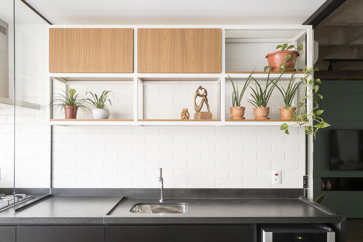 Wall in white tiles with greenery and small shelving in the kitchen