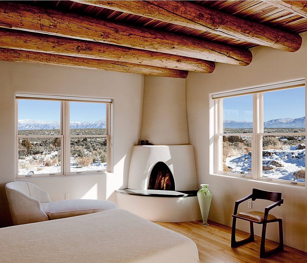 Wooden-logs-acting-as-ceiling-beams-in-the-cozy-Mediterranean-style-bedroom-with-fireplace-in-the-corner