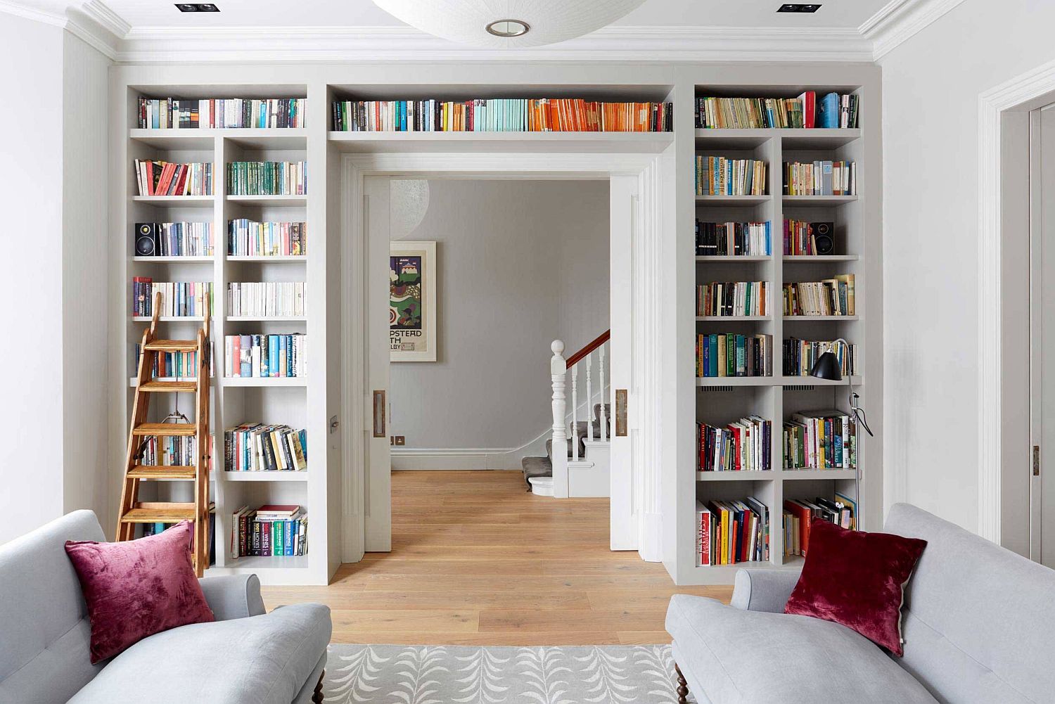 Bookshelf that wraps itself around the doorway helps create a lovely wall of books in the living room with ample natural light