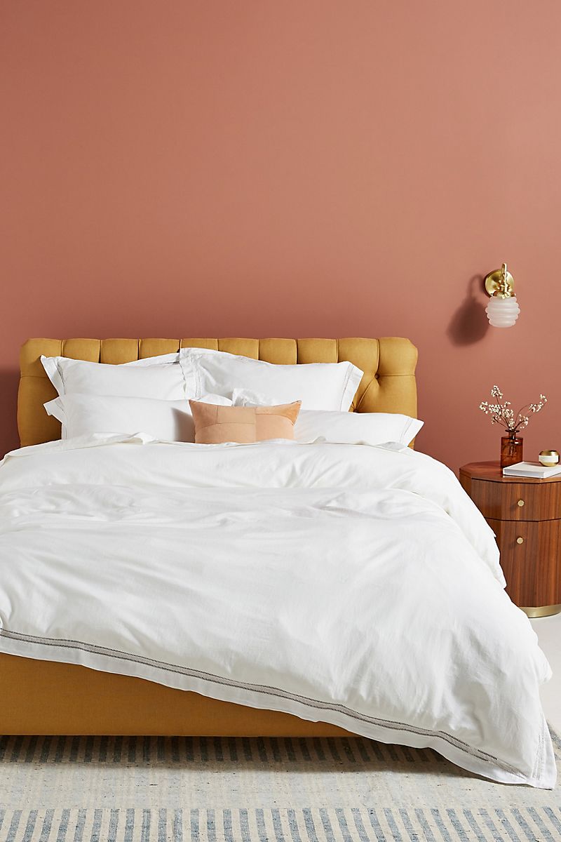 Comfy bedroom featuring earthy pink walls and a mustard bed