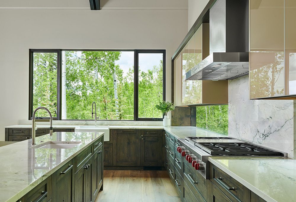 Eat-in-kitchen with dark green cabinets and white marble backsplash is flooded with natural light