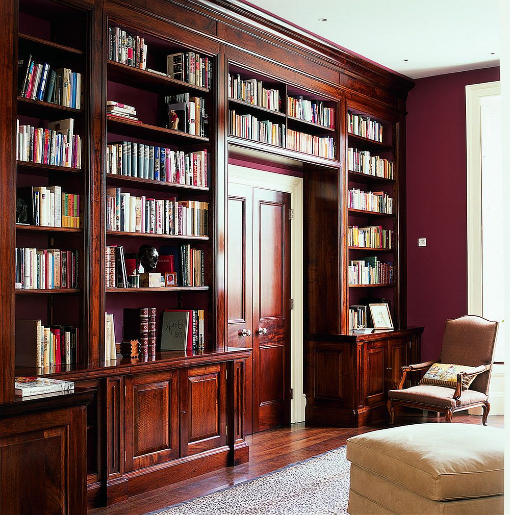 French walnut shelves around the doorway along with red walls shape a classic reading room