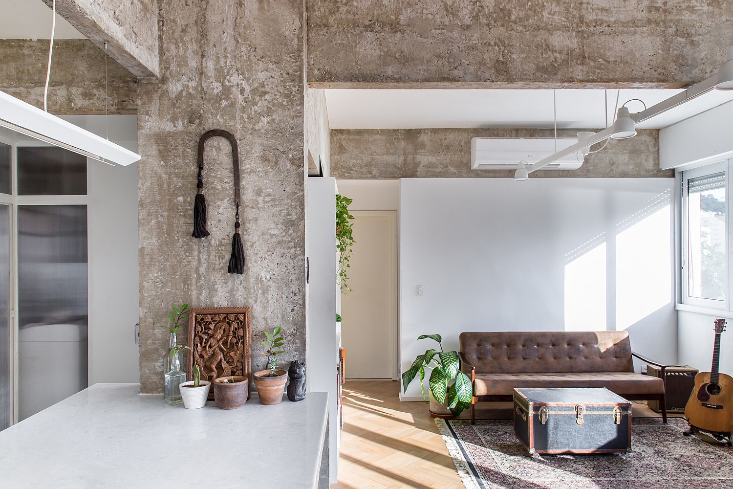 Natural light illuminates the rugged concrete living space of the apartment