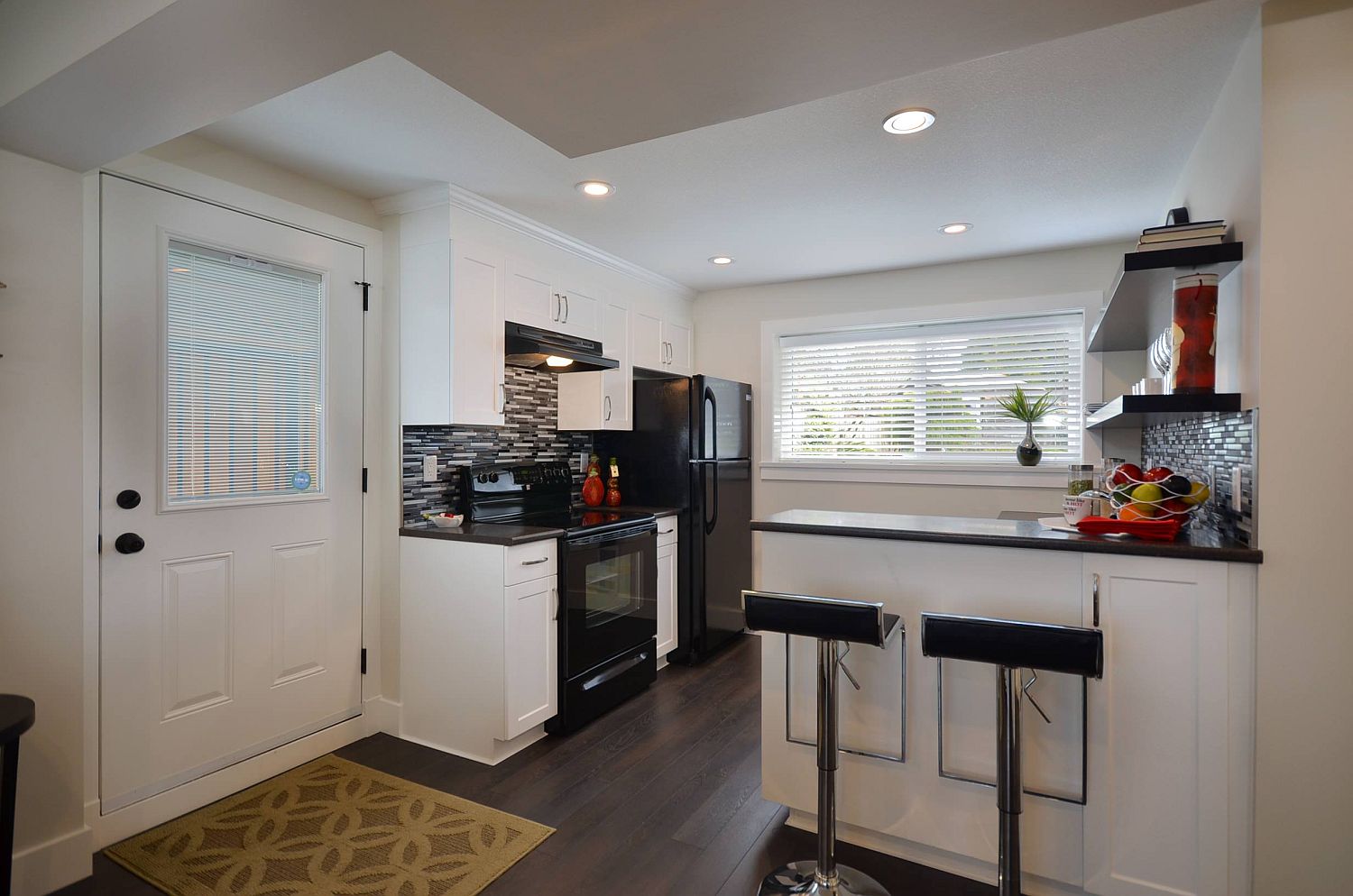 Basement apartment kitchen in white where black appliances stand out even more visually