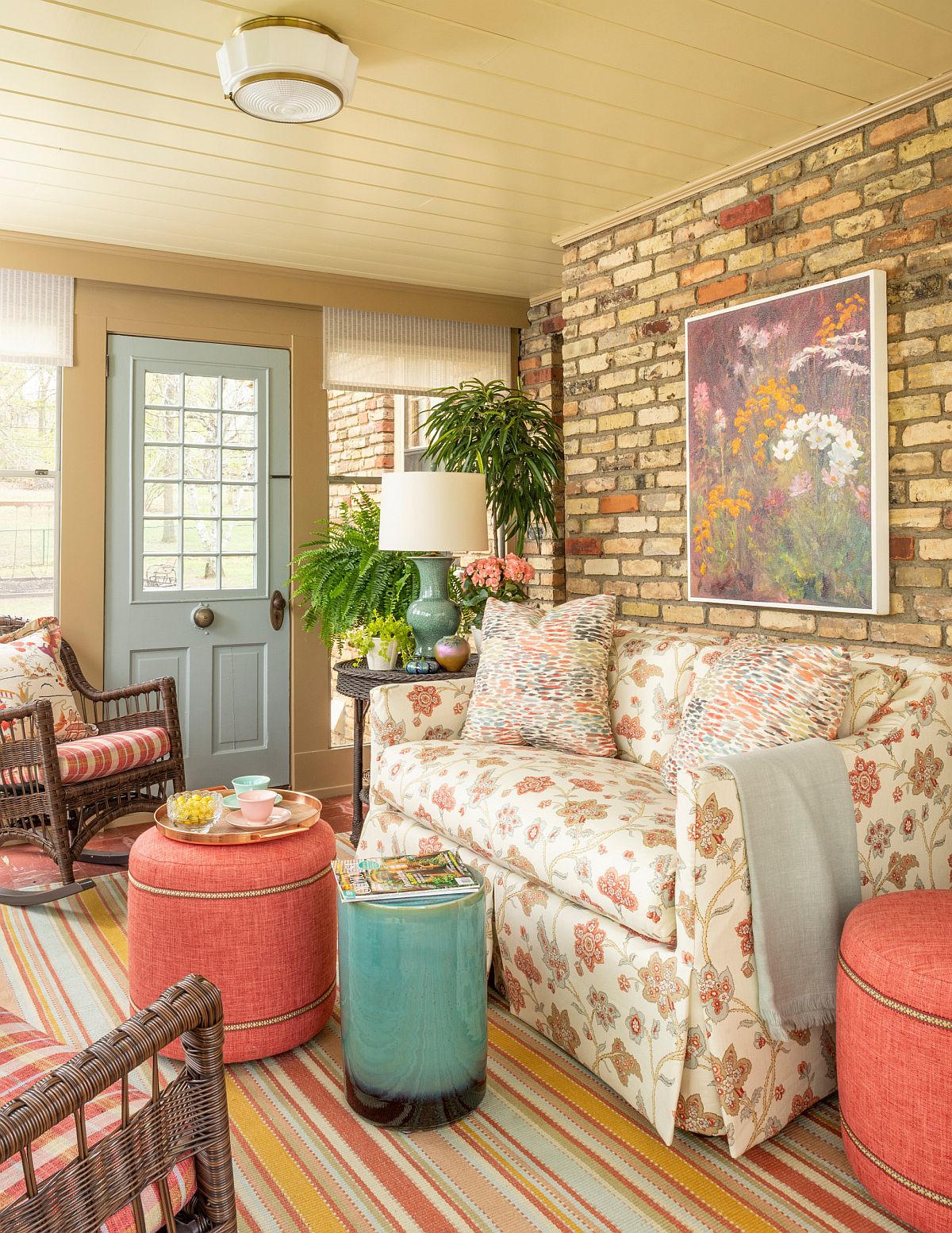 Colorful couch, beautiful pink stools and a smart accent brick wall in the sunroom