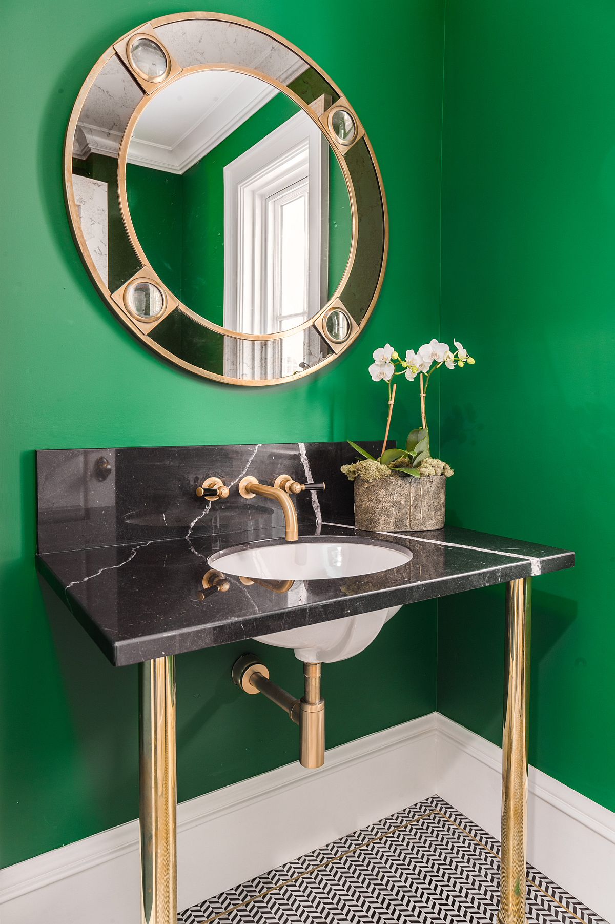 Dark green powder room with gold and black sink and matching mirror frame