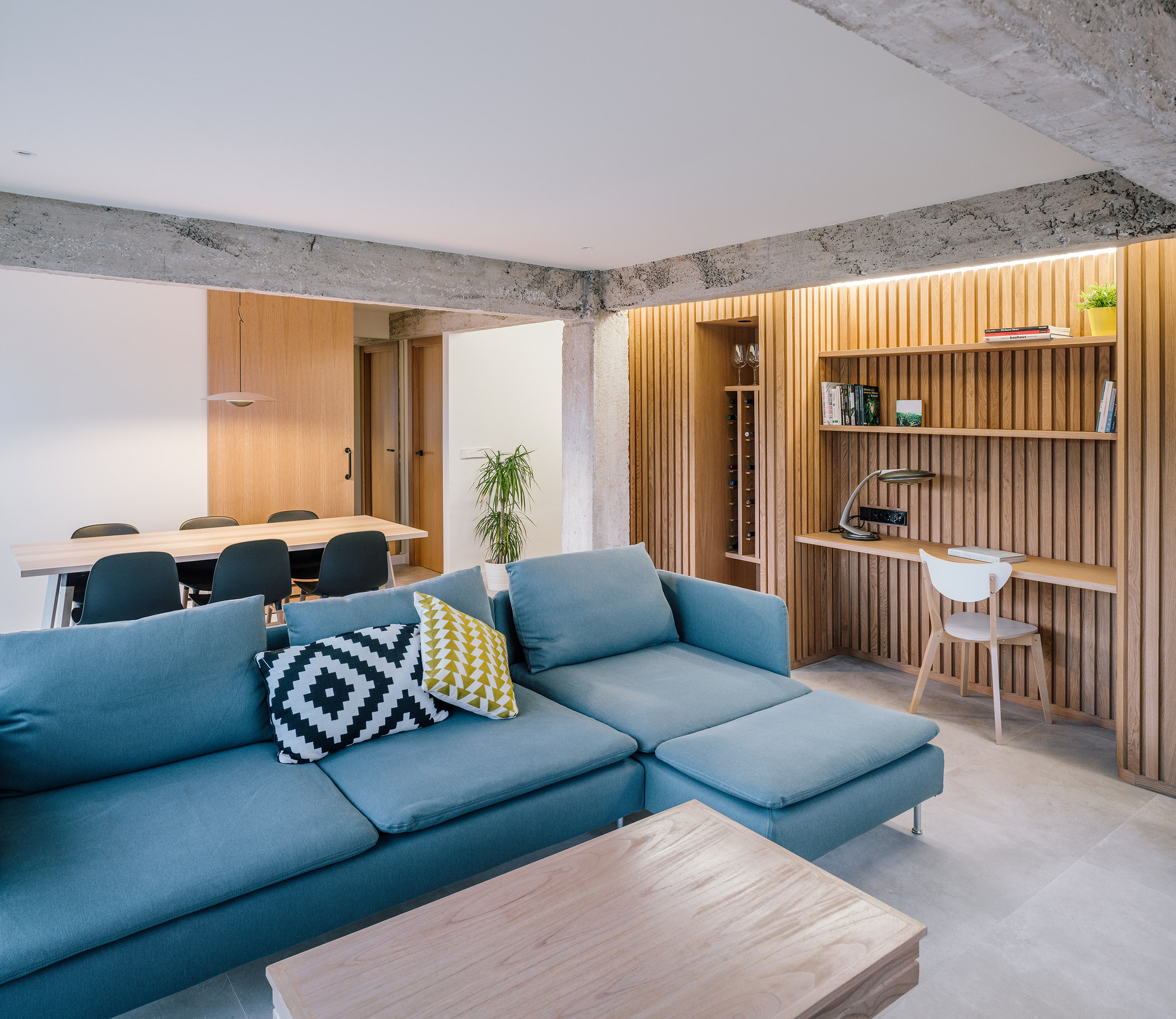 Fabulous blue sectional steals the show in the new living area thanks to the neutral concrete backdrop