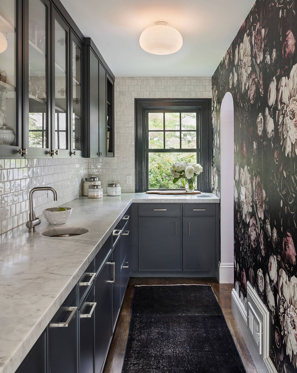 Flowery wallpaper covers an entire wall in this narrow kitchen and gives it a dashing, unique aesthetic