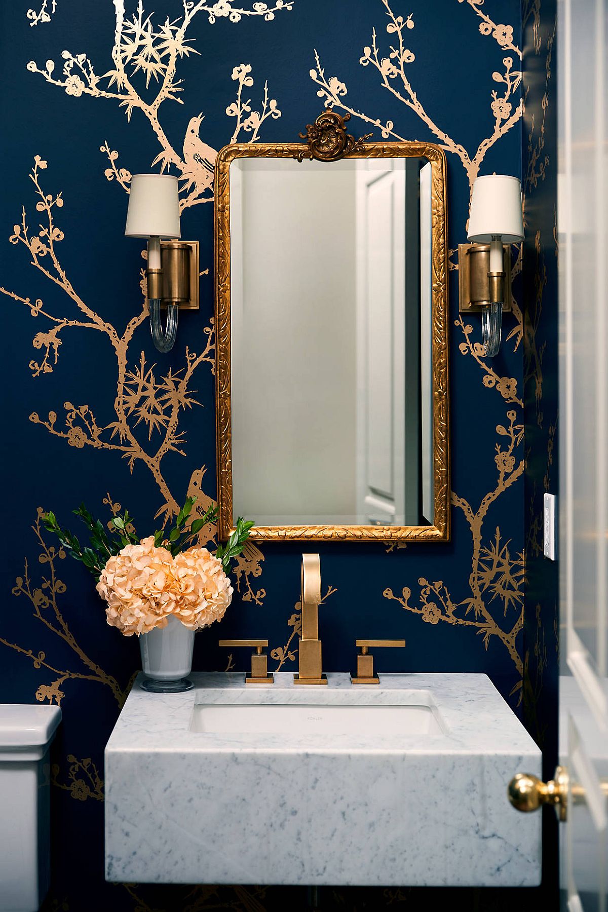 Glamarous blend of gold and dark blue in the contemporary powder room with white vanity