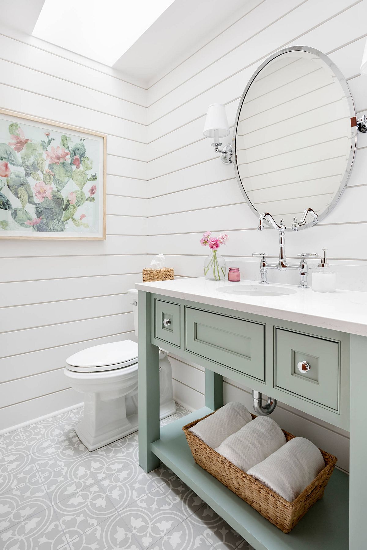 Gorgeous powder room in white with pastel green vanity and a skylight that brings in natural light