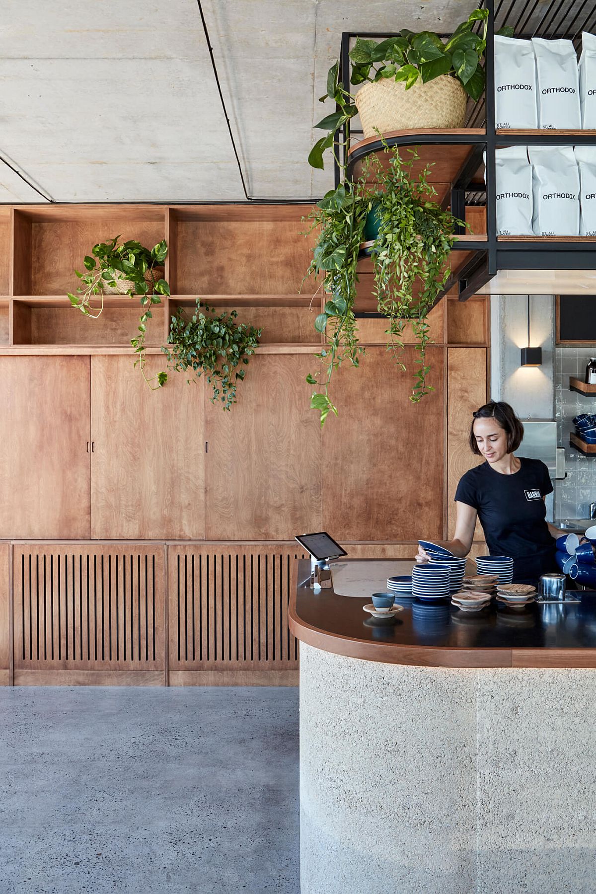 Greenery brings life to the raw concrete, wood and rammed earth restaurant interior