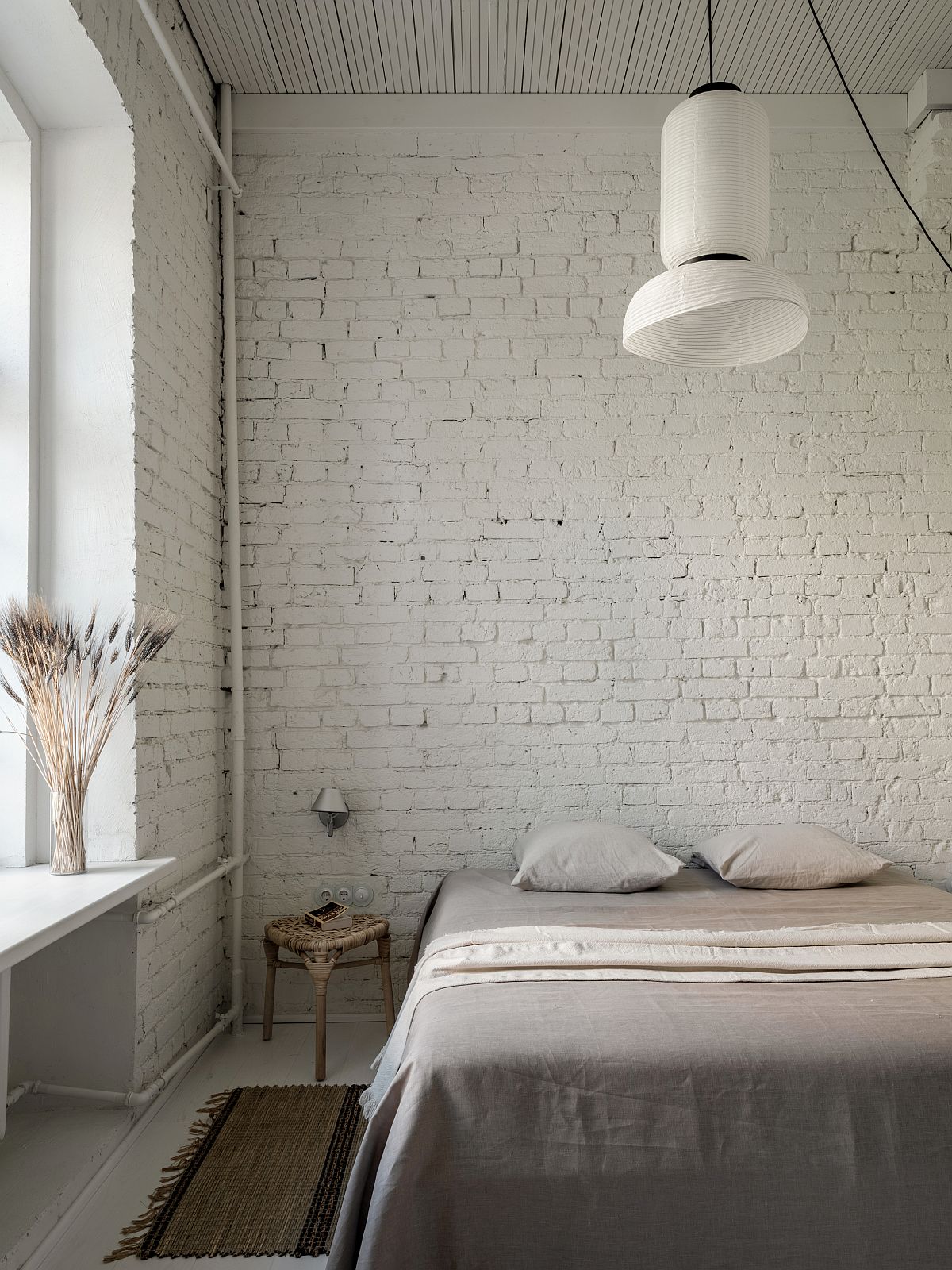 Large-pendant-light-in-white-along-with-a-window-illuminate-the-white-bedroom-with-brick-wall-94274