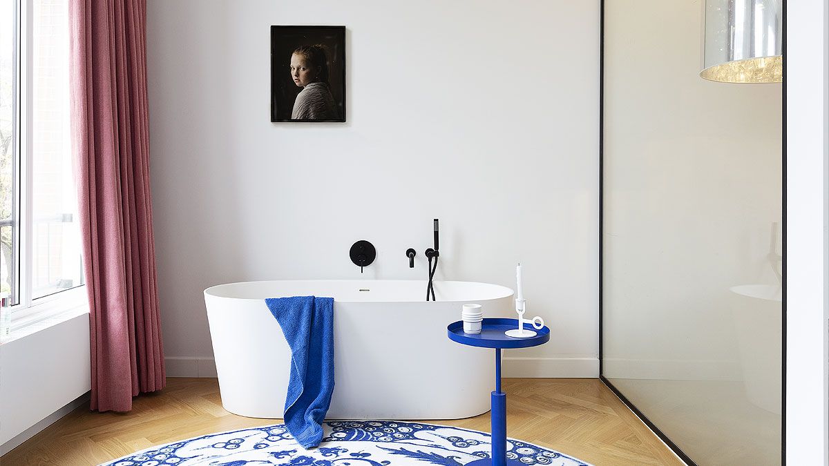 Little side table in classic blue sits elegantly next to the freestanding bathtub inside the spa-styled bathroom