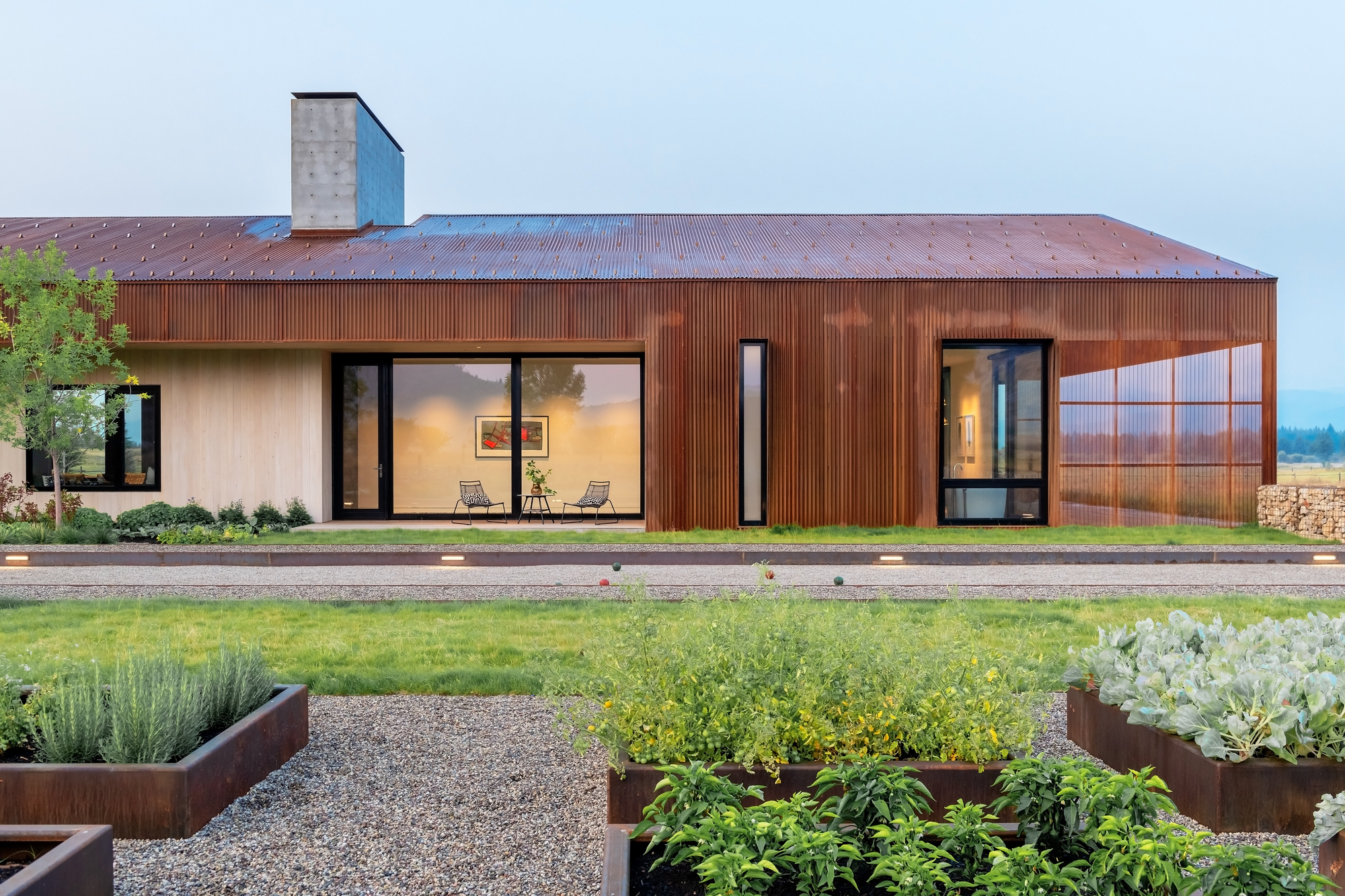 Oxidized metal wood and glass shape the exterior of the asymmetrical Dogtrot House